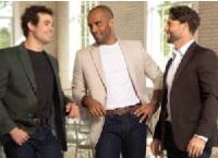 Three men standing and conversing indoors